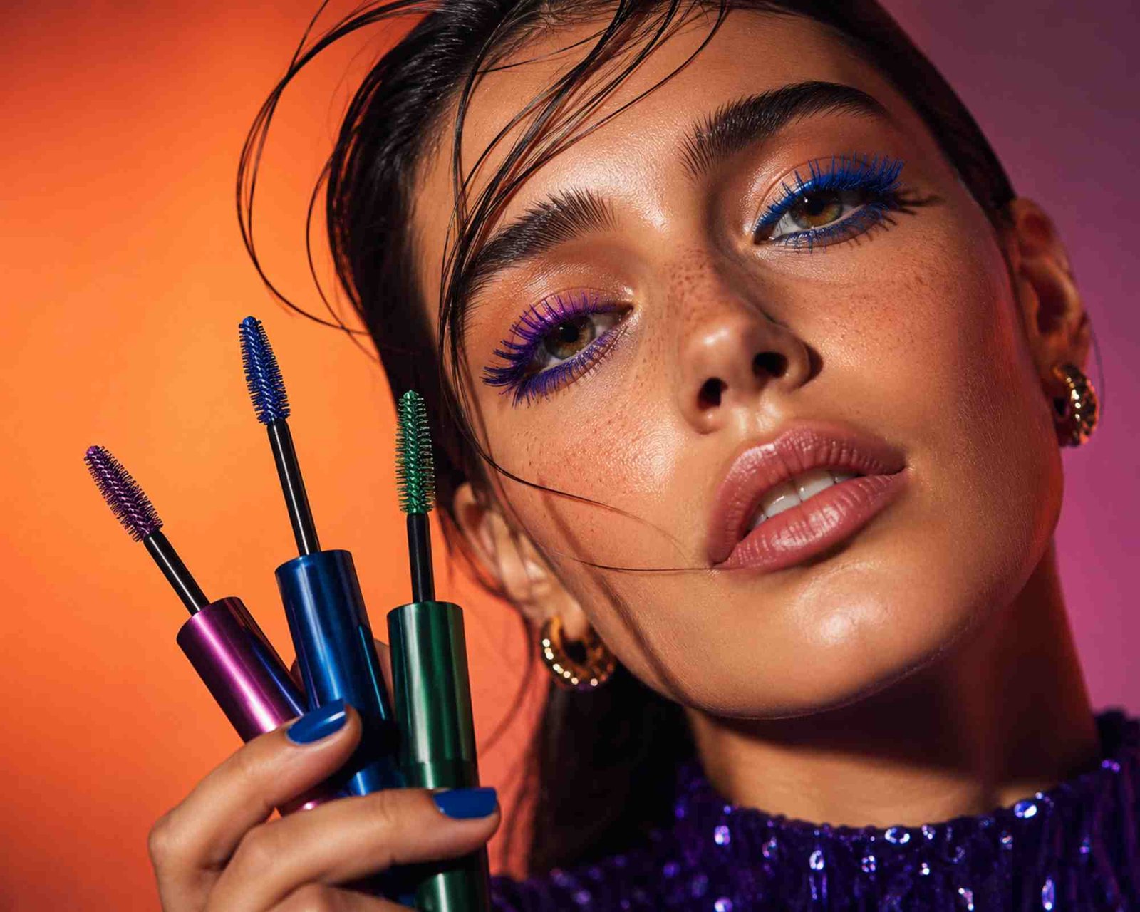 una donna ha in mano tre mascara colorati, scatto da set di moda
