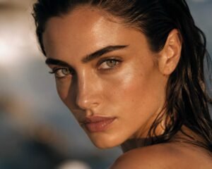 Una donna guarda fissa l'obiettivo al tramonto, ha i capelli bagnati e sguardo profondo